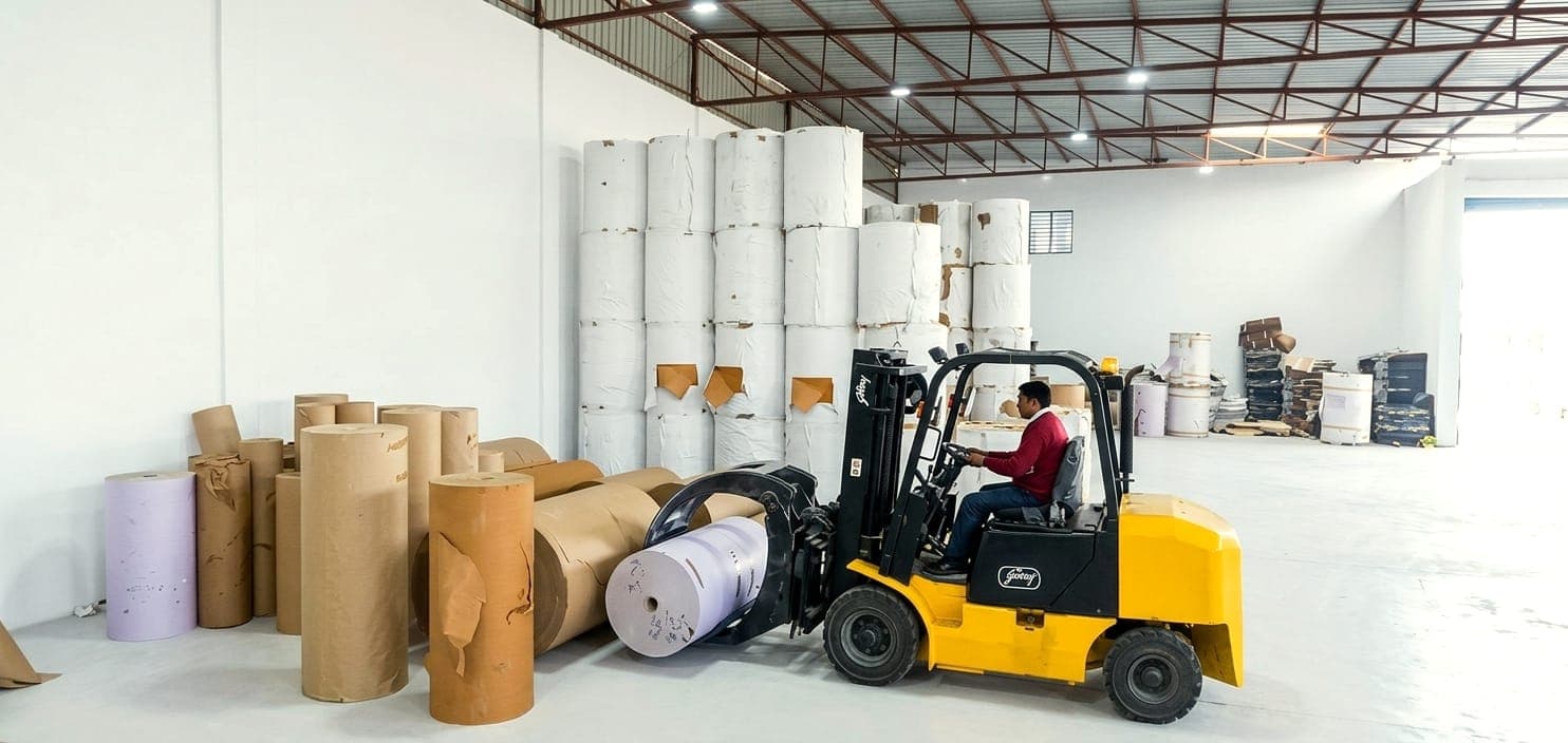 Raw material storage warehouse with paper rolls and forklift